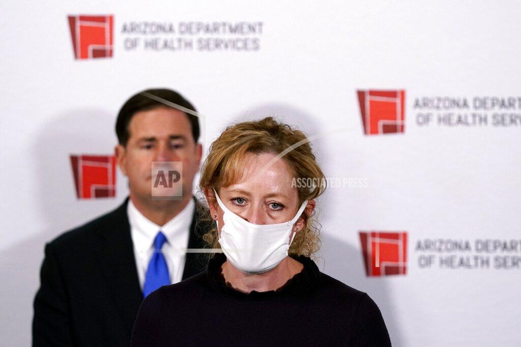 FILE - In this Wednesday, Dec. 2, 2020 file photo Arizona Department of Health Services Director Dr. Cara Christ speaks as Republican Arizona Gov. Doug Ducey listens during a news conference, in Phoenix. Arizona expects to get enough doses of a new coronavirus vaccine by the end of the year to inoculate more than 383,000 health care workers and long-term care facility residents, Dr. Christ said Friday, Dec. 4, 2020. (AP Photo/Ross D. Franklin, Pool, File)