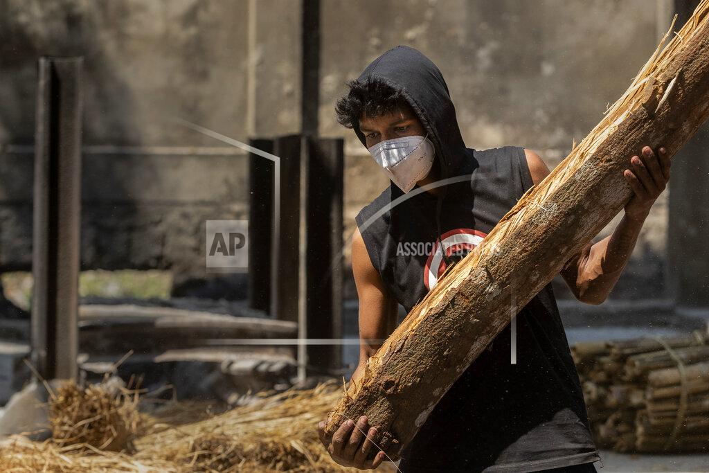Anupam Nath A man carries a log to cremate the body of a person who died of COVID-19 in Gauhati, India, Tuesday, April 27, 2021. The COVID-19 death toll in India has topped 200,000 as the country endures its darkest chapter of the pandemic yet. (AP Photo/Anupam Nath)
