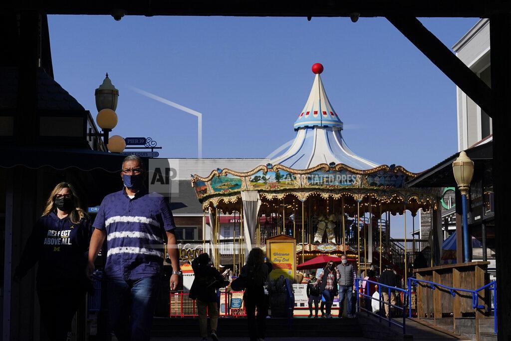 Jeff Chiu FILE - In this Nov. 12, 2020, file photo, people wear face masks while walking in front of the carousel at Pier 39 during the coronavirus outbreak in San Francisco. With the coronavirus coming back with a vengeance across the country and the U.S. facing a long, dark winter, governors and other elected officials are showing little appetite for reimposing the kind of lockdowns and large-scale business closings seen last spring. (AP Photo/Jeff Chiu, File)