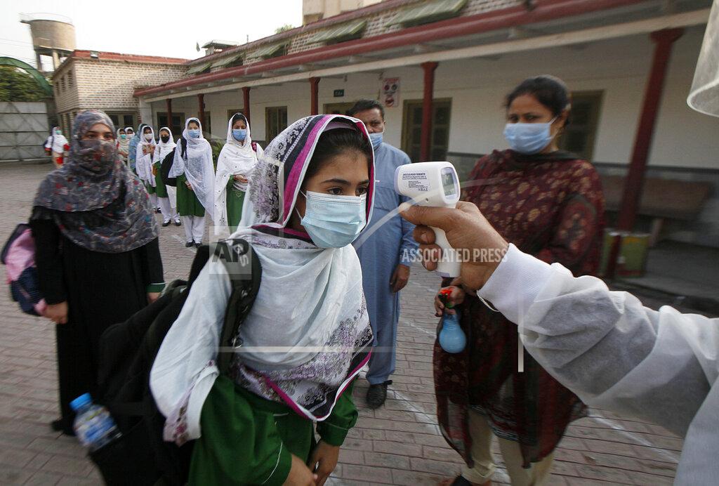 Muhammad Sajjad A worker checks body temperature of students upon her arrival at a school in Peshawar, Pakistan, Wednesday, Sept. 23, 2020. Pakistani officials welcomed millions of students back to middle schools following educational institutions reopened in the country amid a steady decline in coronavirus deaths and infections. (AP Photo/Muhammad Sajjad)