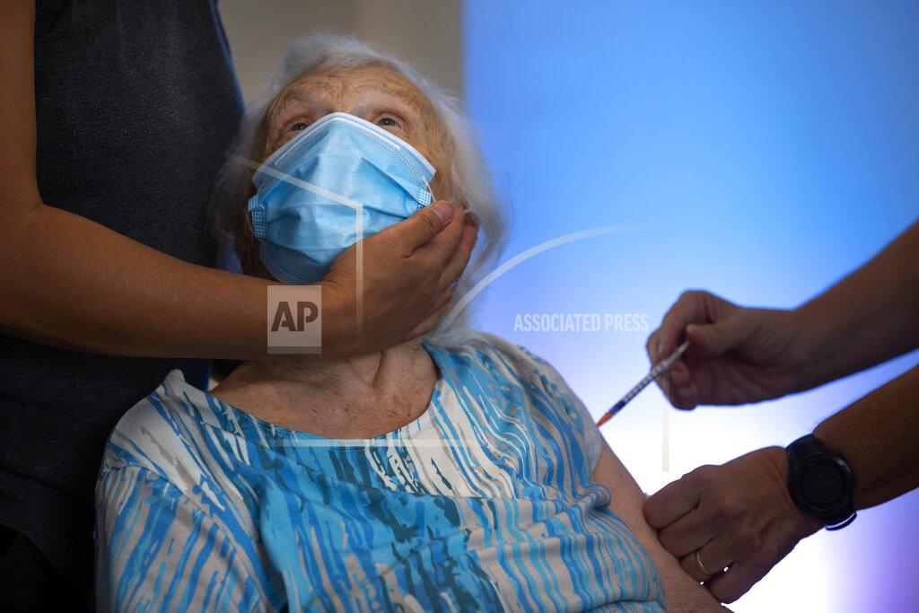 Oded Balilty Blossom Koppelman, 86, receives a third Pfizer-BioNTech COVID-19 vaccine from a Magen David Adom national emergency service volunteer, at a private nursing home, in Netanya, Israel, Sunday, Aug. 1, 2021. Israeli health authorities began administering coronavirus booster shots on Friday to people over 60 who've already received both doses of a vaccine, in a bid to combat a recent spike in cases. (AP Photo/Oded Balilty)