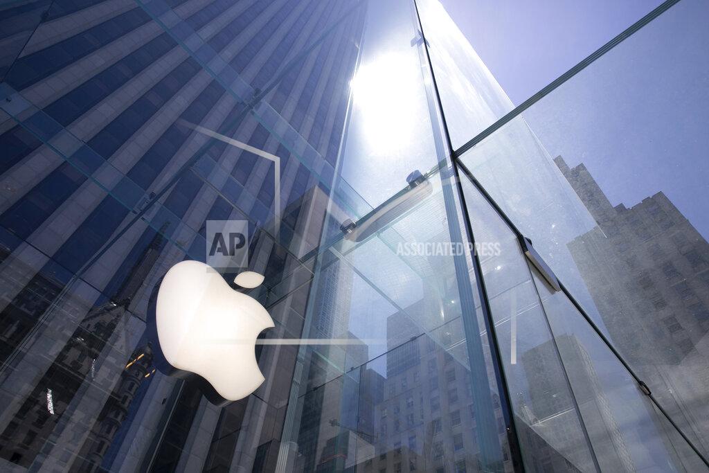 FILE - In this Tuesday, June 16, 2020 file photo, the sun is reflected on Apple's Fifth Avenue store in New York. Apple has managed to shine amid the gloom, putting it on the cusp of becoming the first U.S. company to boast a market value of $2 trillion, just two years after it became the first to reach $1 trillion. With its stock already up 50% this year, the only question among analysts is whether Apple will pass the $2 trillion milestone before the release of its next-generation iPhones in October.(AP Photo/Mark Lennihan, File)