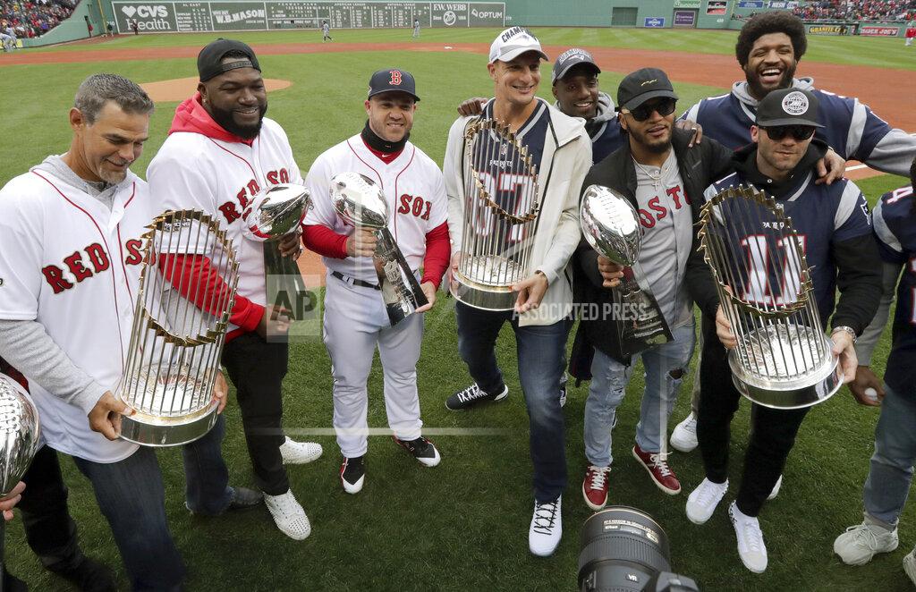 Charles Krupa New England Patriots and Boston Red Sox players hold Super Bowl and World Series trophies before the home opener baseball game between the Red Sox and the Toronto Blue Jays, Tuesday, April 9, 2019, in Boston. From left they are, Red Sox's Mike Lowell, David Ortiz and Steve Pearce, Patriots' Rob Gronkowski, Patrick Chung and Julian Edelman. At rear are Duron Harmon, behind Gronkowski, and Deatrich Wise, behind Edelman. (AP Photo/Charles Krupa)