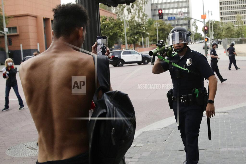 Jae C. Hong FILE - In this June 2, 2020, file photo, a police officer aims his less-lethal weapon at a demonstrator during a protest in Los Angeles. Two reviews of the violence that surrounded last summer’s police brutality protests in Los Angeles say the LAPD wasn’t prepared to react when peaceful demonstrations were marred by clashes, vandalism and looting. The Los Angeles Times says the reports, released Friday, April 9, 2021 found that poor planning, inconsistent leadership and inadequate training contributed to disorder in the streets that caused an estimated $167 million in losses to private property and businesses owners. (AP Photo/Jae C. Hong, File)