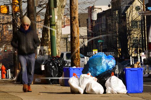 Trash sits out for collection in Philadelphia, Thursday, Jan. 13, 2022. The omicron variant is sickening so many sanitation workers around the U.S. that waste collection in Philadelphia and other cities has been delayed or suspended. (AP Photo/Matt Rourke)