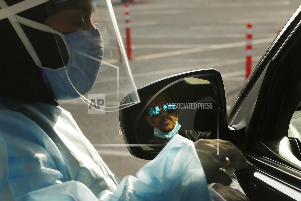 Amr Nabil Saudi health worker, Wedad Modaifen prepares to collect a swab sample for a polymerase chain reaction (PCR) test at drive-through testing center at King Abdulaziz University in Jiddah, Saudi Arabia Wednesday, Feb. 3, 2021. In Saudi Arabia, where authorities already have banned travel to the kingdom from 20 countries including the U.S., officials ordered all weddings and parties suspended. It closed down all shopping malls, gyms and other locations for 10 days, as well as indoor dining. Authorities warned the new measures could be extended. (AP Photo/Amr Nabil)