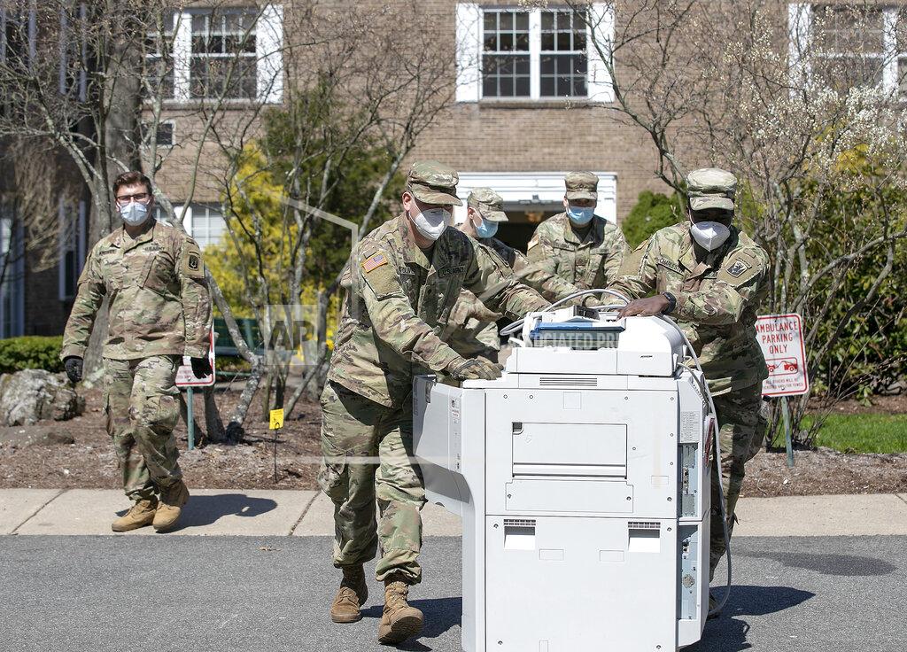 Connecticut National Guard reserve soldiers remove old office equipment from storage while setting up more than 30 beds for recovering COVID-19 patients at Quinnipiac Valley Center, Wed., Apr. 15, 2020. The center is sixth on the state's list of facilities being designated for COVID-19 patient recovery. (Dave Zajac/Record-Journal via AP)