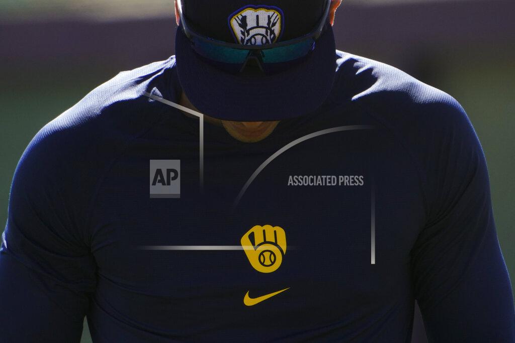 Milwaukee Brewers' Christian Yelich walks past a batting cage during the team's spring training baseball workout in Phoenix, Tuesday, Feb. 23, 2021. (AP Photo/Jae C. Hong)