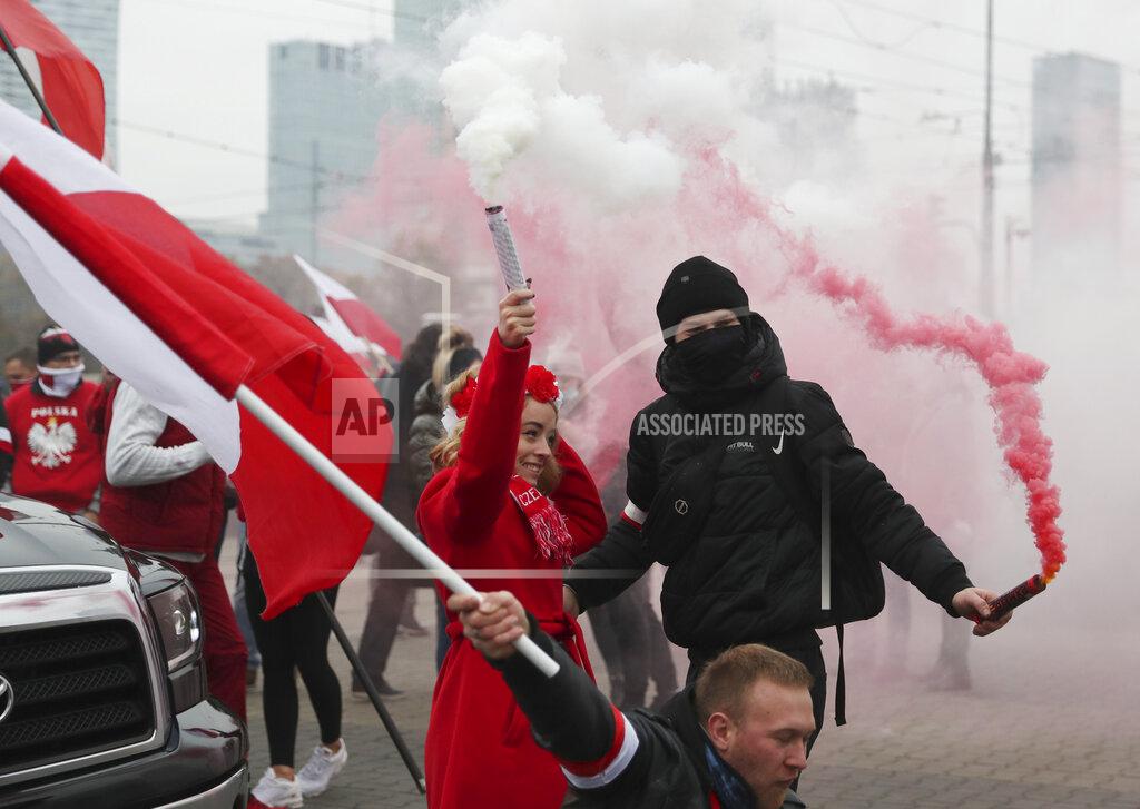 Protesters burn down bengal fire as they attend in the annual Independence Day march organized by far-right groups for participants to be inside cars or motorbikes because of the coronavirus social distancing, ready for the start of the event in Warsaw, Poland, Wednesday, Nov. 11, 2020. The march that marks Poland's sovereignty regained after World War I has often led to clashes with opponents. (AP Photo/Czarek Sokolowski)
