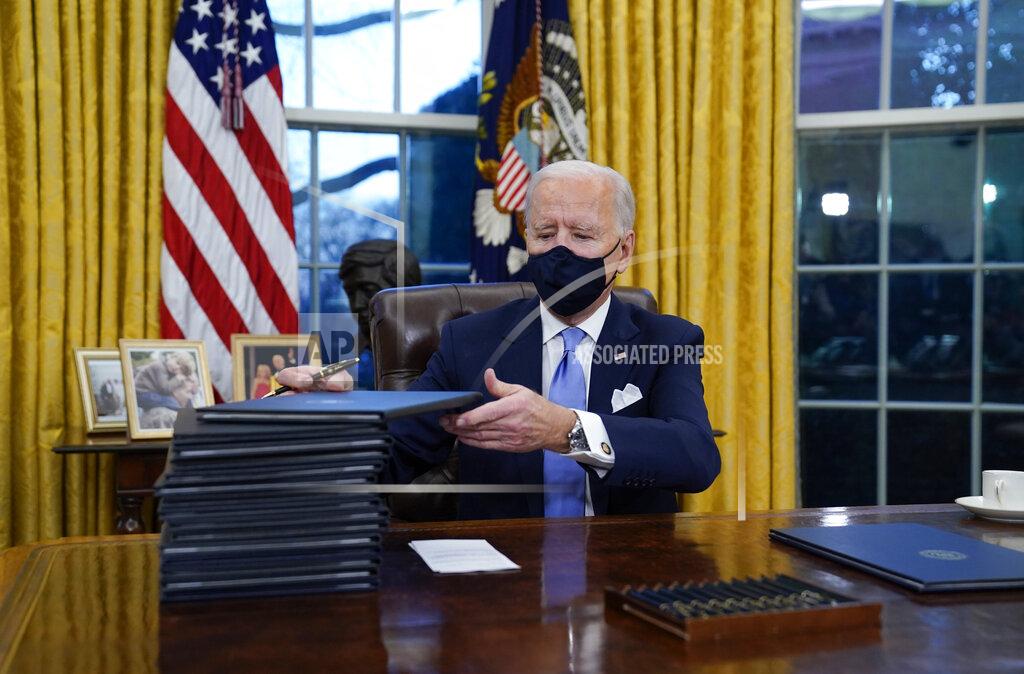 FILE - In this Jan. 20, 2021, file photo, President Joe Biden signs his first executive orders in the Oval Office of the White House in Washington. Thousands of people are waiting to claim asylum and more come each day, falsely believing they will be able to enter the U.S. now that former President Donald Trump is out of office. Biden has made major changes to his predecessor's hardline immigration policies; but he hasn't lifted the major restrictions to people seeking asylum as he faces pressures from all sides. (AP Photo/Evan Vucci, File)