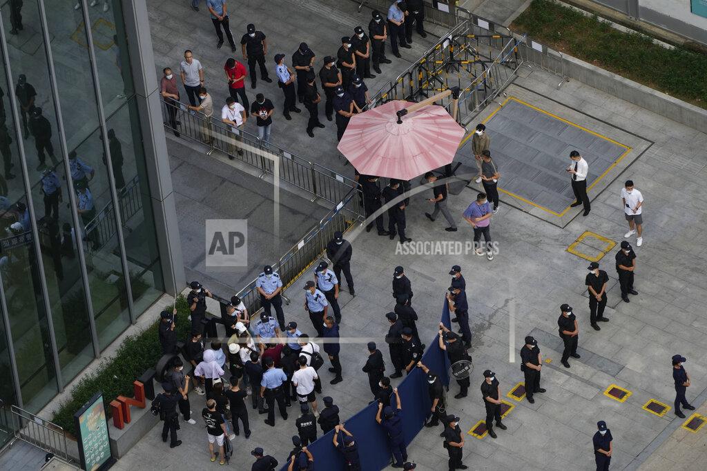 Ng Han Guan Investors are surrounded by police and security personnel as they try to enter the headquarters of the real estate developer Evergrande Group, Thursday, Sept. 23, 2021, in Shenzhen, southern China. Fears that the developer's possible default on multibillion-dollar debts might send shockwaves through global financial markets appeared to ease Thursday as creditors waited to see how much they might recover. (AP Photo/Ng Han Guan)