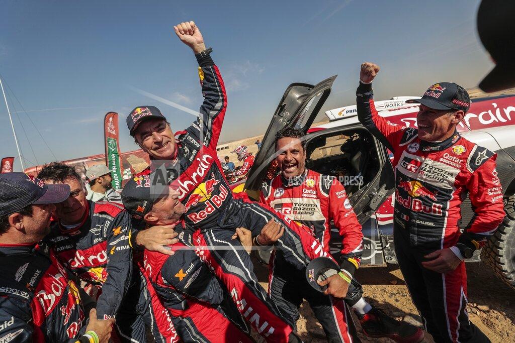 Bernat Armangue Driver Carlos Sainz, of Spain, center, is lifted by Driver StÈphane Peterhansel, of France, center and left, and driver Nasser Al-Attiyah, of Qatar, center and right, at the end of stage twelve of the Dakar Rally between Haradth and Qiddiya, Saudi Arabia, Friday, Jan. 17, 2020. (AP Photo/Bernat Armangue)