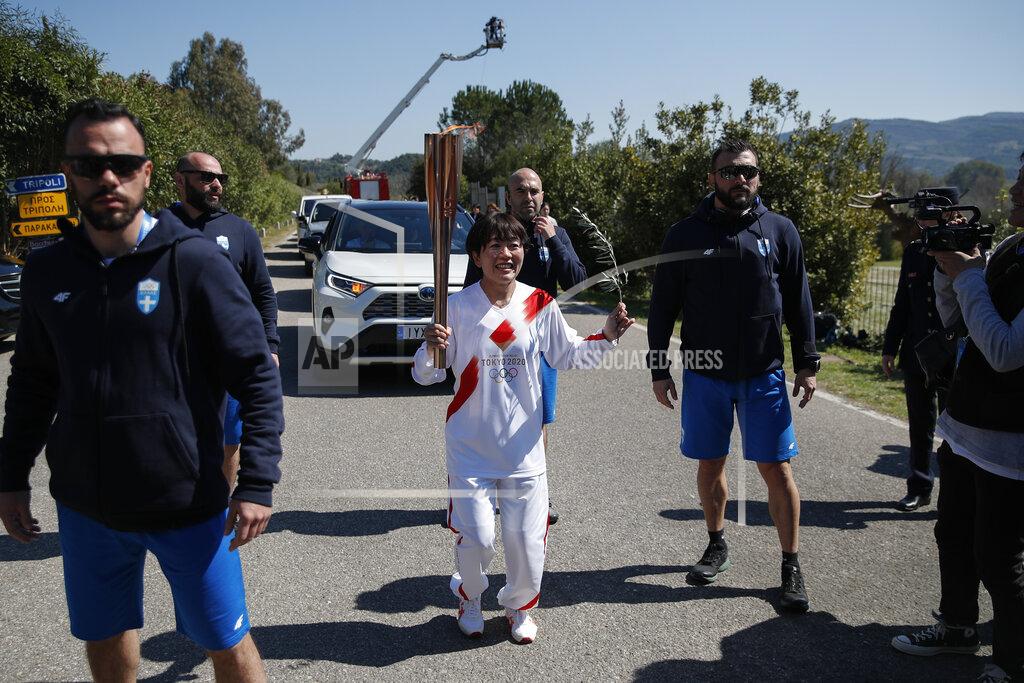 Thanassis Stavrakis Japanese Olympic marathon champion, Mizuki Noguch, center, the second torchbearer, holds the torch of the 2020 Tokyo Olympic Games following the flame lighting ceremony at the closed Ancient Olympia site, birthplace of the ancient Olympics in southern Greece, Thursday, March 12, 2020. Greek Olympic officials are holding a pared-down flame-lighting ceremony for the Tokyo Games due to concerns over the spread of the coronavirus. Both Wednesday's dress rehearsal and Thursday's lighting ceremony are closed to the public, while organizers have slashed the number of officials from the International Olympic Committee and the Tokyo Organizing Committee, as well as journalists at the flame-lighting. (AP Photo/Thanassis Stavrakis)