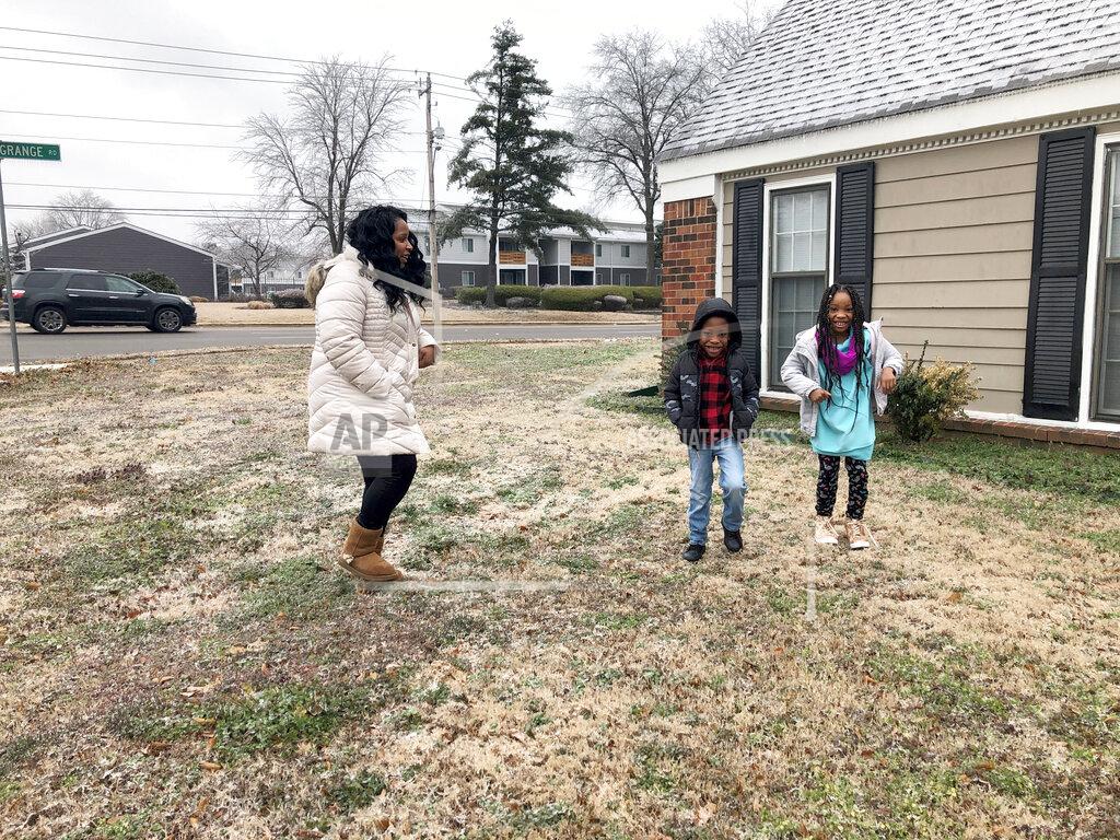 Leah Williamson, left, and her twin 7-year-old children Carpenter Adoo, center, and Sira Joy Adoo jump on the icy, frozen ground outside their home on Saturday, Feb. 13, 2021, in Memphis, Tenn. Carpenter's medical condition makes him particularly vulnerable to COVID-19, putting him in a population that states are wrestling with how to prioritize as vaccine supplies fall short of demand. Tennessee last month joined a handful of states in moving the families of medically frail children like Carpenter up the vaccine priority list. (AP Photo/Adrian Sainz)