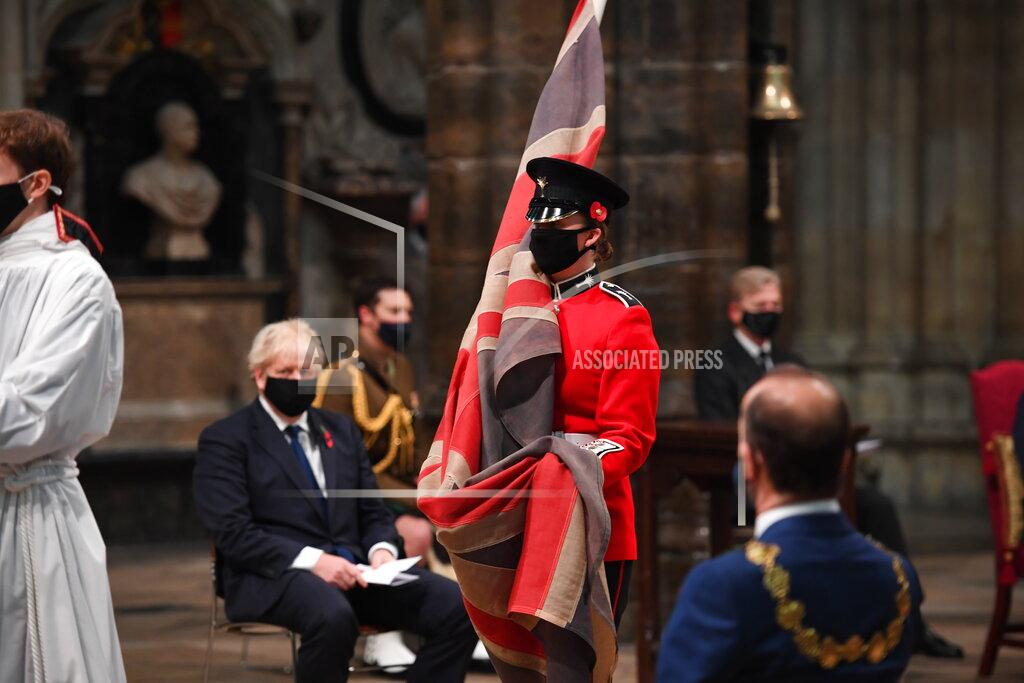 Jeremy Selwyn The Padre’s flag, the British Union flag that was used by the Reverend David Railton as an altar cloth on the battlefields of northern France during World War I, is carried through Westminster Abbey to be laid on the altar by Guardsman Rhian Morgan of the 1st Battalion Welsh Guards, watched by honoured guests including Prime Minister Boris Johnson, left, attending the Armistice Day service at Westminster Abbey in London, Wednesday, Nov. 11, 2020. The specially arranged service, with social distancing because of the coronavirus, commemorates the 102nd anniversary of the armistice ending World War I, and one hundred years since the symbolic interment of the Unknown Warrior at Westminster Abbey. David Railton used the flag as an altar cloth during the War in Ypres, when he first thought of the idea of the unknown warrior. (Jeremy Selwyn/Pool via AP)
