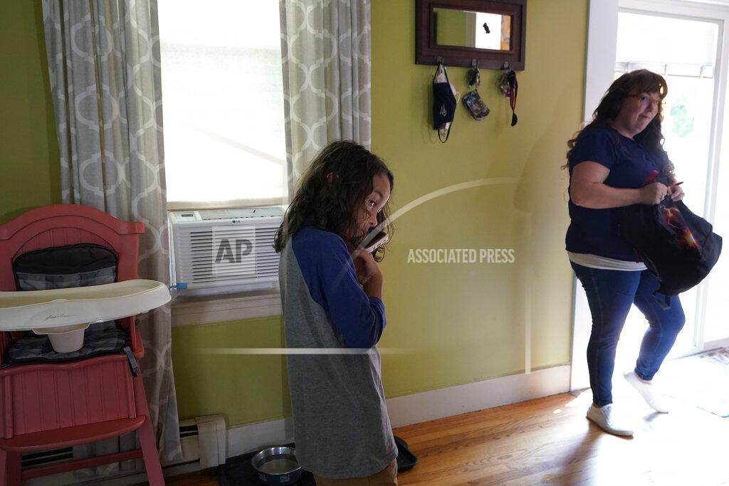 Steven Senne Gabriel Andrade-Cullen, 9, left, son of Allison Cullen, right, both of Brockton, Mass., speaks on the phone with his father Flavio Andrade Prado, from their home in Brockton, Thursday, July, 22, 2021. Prado, a Brazilian national, is being held by Immigration and Customs Enforcement, or ICE, at the Plymouth County House of Corrections. Cullen, a mother of two, says she and her children haven't been able to visit her husband since before the pandemic. (AP Photo/Steven Senne)