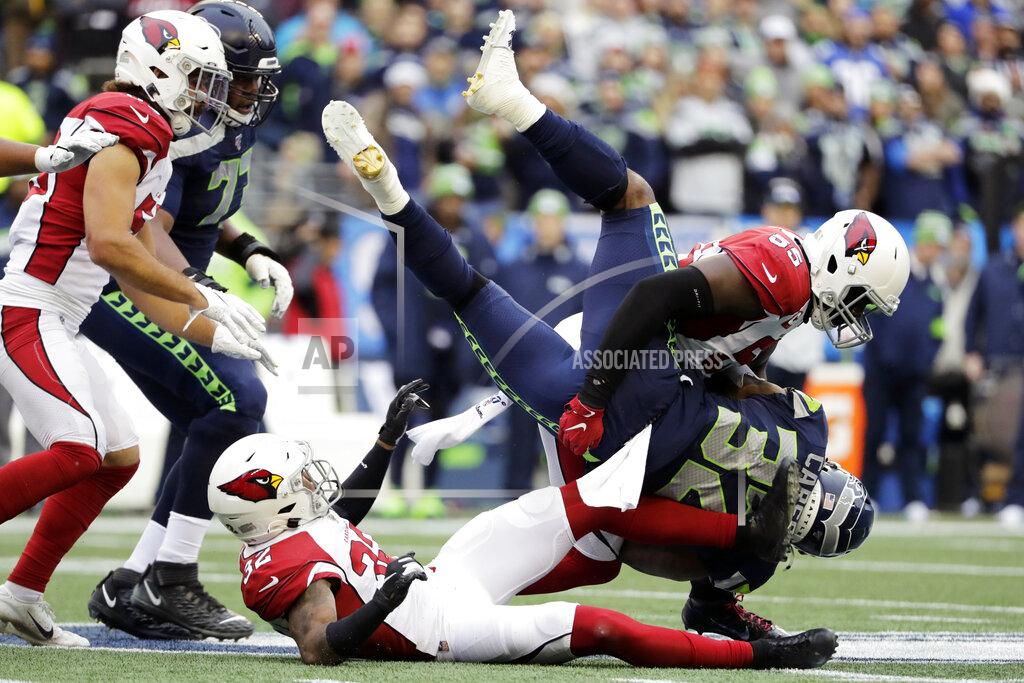 Lindsey Wasson Seattle Seahawks running back Chris Carson (32) is tackled by Arizona Cardinals linebacker Chandler Jones (55) above Cardinals strong safety Budda Baker, lower left, during the first half of an NFL football game, Sunday, Dec. 22, 2019, in Seattle. (AP Photo/Lindsey Wasson)