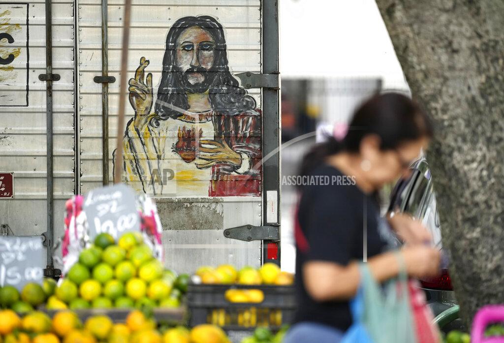 Silvia Izquierdo A woman walks past a fruit vendor at a street market in Rio de Janeiro, Brazil, Wednesday, May 11, 2022. High inflation in Brazil is eroding the buying power of consumers and angering potential voters, who fault President Jair Bolsonaro for not doing enough about it. (AP Photo/Silvia Izquierdo)
