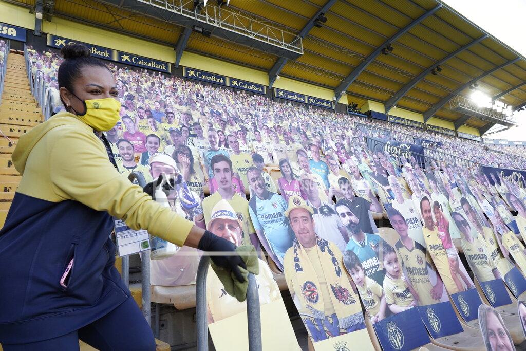 Alberto Saiz A stadium members cleans the stands as cardboard cut-out of fans are placed on the seats ahead of the Spanish La Liga soccer match between Villarreal and Real Madrid in Ceramica stadium in Villarreal, Spain, Saturday Nov. 21, 2020. (AP Photo/Alberto Saiz)