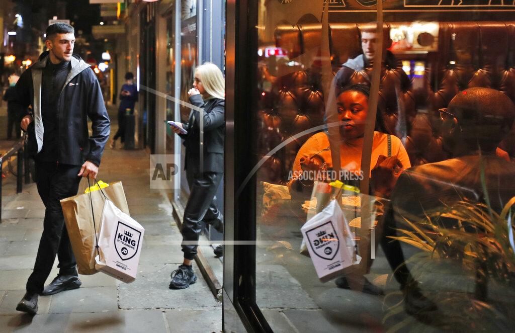 Frank Augstein Shoppers walk past people eating in a restaurant in Liverpool, England, Wednesday, Oct. 14, 2020. As the first area in England slapped with strict new restrictions to curb the resurgent coronavirus that have shuttered pubs and imperiled thousands of jobs, Liverpool again feels it's being punished by policies made in Britain's capital, 180 miles (290 kilometers) to the south. (AP Photo/Frank Augstein)