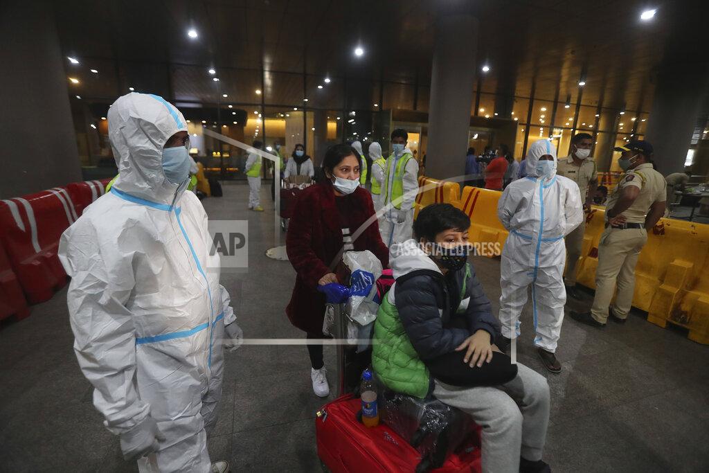 Rafiq Maqbool Indian municipal workers in personal protective equipment (PPE) guide passengers arriving from United Kingdom, at Chhatrapati Shivaji Maharaj International Airport in Mumbai, India, Tuesday, Dec. 22, 2020. Dozens of countries around the world slapped tough travel restrictions on the U.K. because of a new and seemingly more contagious strain of the coronavirus in England. From Canada to India, one nation after another banned flights from Britain. (AP Photo/Rafiq Maqbool)