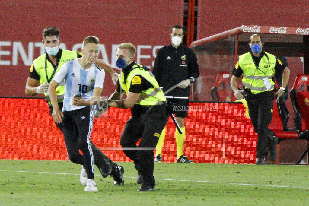 Francisco Ubilla A supporter invades the pitch during the Spanish La Liga soccer match between Mallorca and FC Barcelona at Son Moix Stadium in Palma de Mallorca, Spain, Saturday, June 13, 2020. With virtual crowds, daily matches and lots of testing for the coronavirus, soccer is coming back to Spain. The Spanish league resumes this week more than three months after it was suspended because of the COVID-19 pandemic. (AP Photo/Francisco Ubilla)
