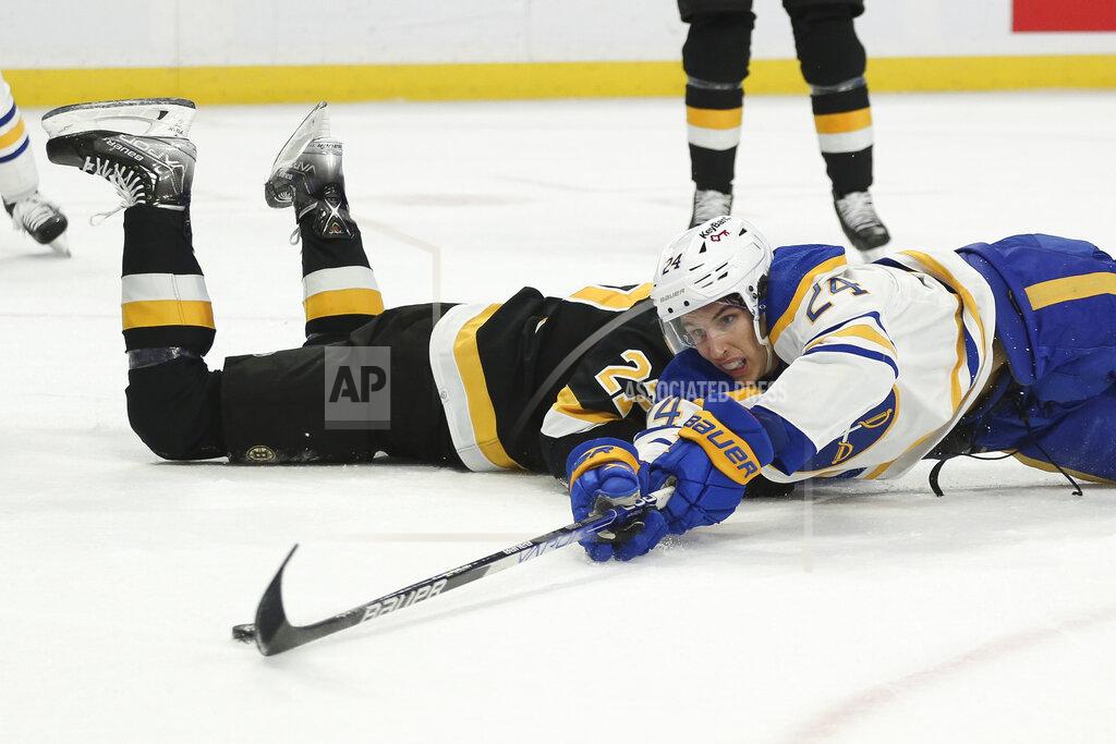 Joshua Bessex Buffalo Sabres center Dylan Cozens (24) attempts to shoot while falling to ice after colliding with Boston Bruins defenseman John Moore during the first period of an NHL hockey game Friday, Oct. 22, 2021, in Buffalo, N.Y. (AP Photo/Joshua Bessex)