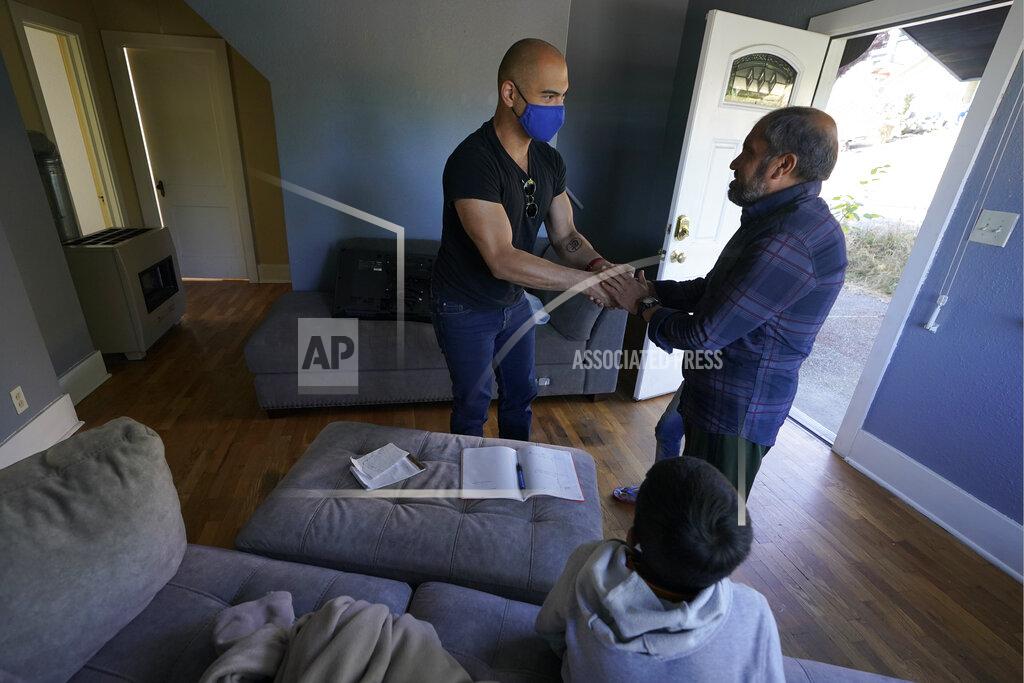 Ted S. Warren Abdul, right, who worked as a mechanic before he left Kabul, Afghanistan with his family about a month ago, shakes hands with Jesse Robbins, left, Thursday, Sept. 16, 2021, after Robbins helped activate internet service in the rental house he owns along with his wife, Thuy Do, who was nine years old when her family arrived in the United States from Vietnam in the 1980s. Do and Robbins have offered their vacant rental home to refugee resettlement groups to house newly arriving Afghans in need of a place to stay. (AP Photo/Ted S. Warren)