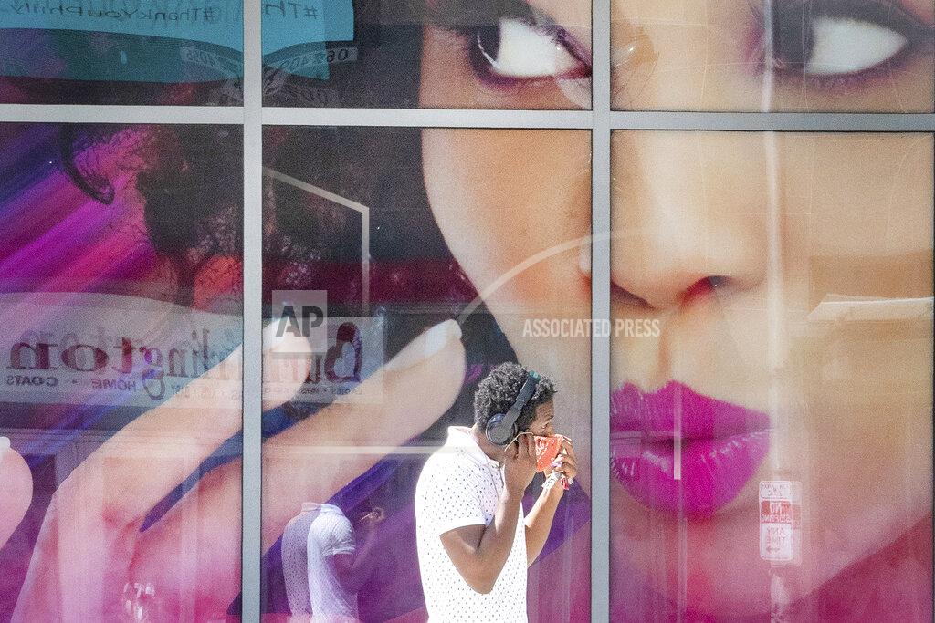 Jose F. Moreno FILE — In this July 28, 2020 file photo, a man places his face mask before entering the Fashion District in Philadelphia. (Jose F. Moreno/The Philadelphia Inquirer via AP)