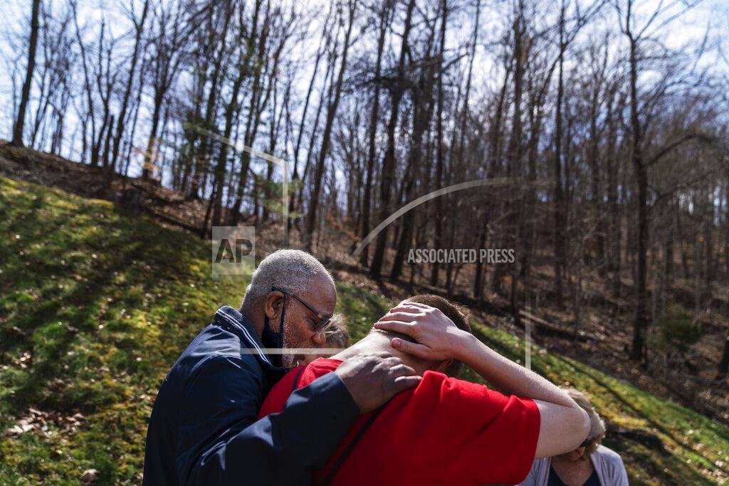David Goldman Quick Response Team member pastor Fred McCarty, prays with a young man who recently overdosed as they visit him at his home in Barboursville, W.Va., Thursday, March 18, 2021. McCarty is one of the faith leaders who ride with the team. When they reach people who overdosed, he asks if they'd like him to pray with them, and usually they say yes. On his keychain he carries the coin he got in 1985, when he finished treatment for his own alcohol addiction. It says "one day at a time," and it's worn down from rubbing his finger across it for more than 30 years. "Recovery is about sharing your strengths and hopes with others," he said. "Our hope is that a lightbulb will come on. And they'll say, if you can do it, I can do it." (AP Photo/David Goldman)