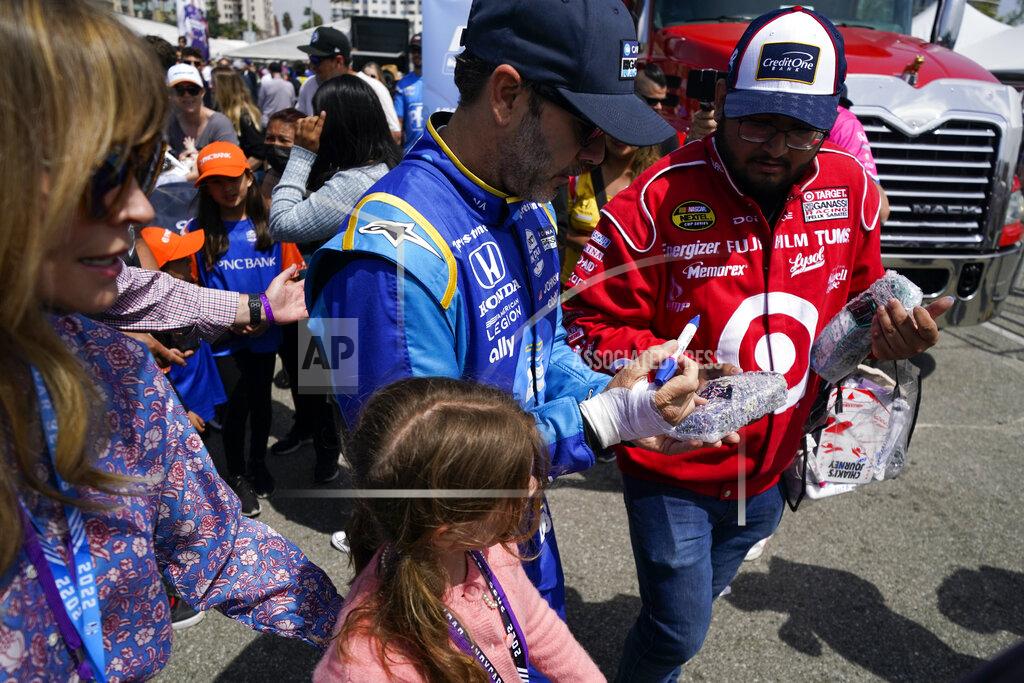 Ashley Landis Chip Ganassi Racing driver Jimmie Johnson, center, of United States signs a an autograph for a fan before an IndyCar auto race at the Grand Prix of Long Beach on Sunday, April 10, 2022, in Long Beach, Calif. Johnson's right hand was injured in a crash on Friday. (AP Photo/Ashley Landis)
