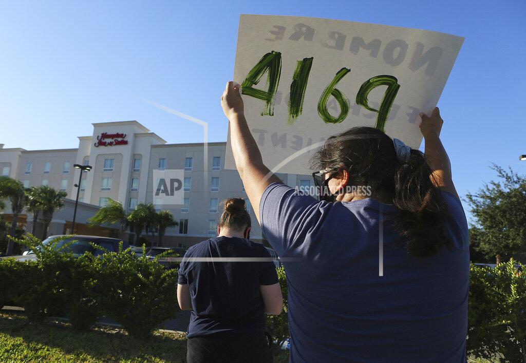 FILE - In this July 23, 2020, file photo, protesters wave signs in front of the Hampton Inn hotel in McAllen, Texas. The Trump administration has sharply increased its use of hotels to detain immigrant children as young as 1 before expelling them from the United States during the coronavirus pandemic despite facing outcry from lawmakers and human-rights advocates. (Joel Martinez/The Monitor via AP, File)