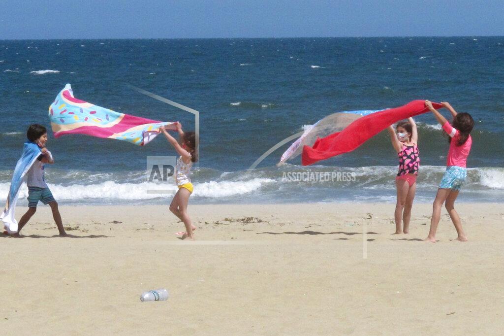 Wayne Parry Children play with beach towels on a windy day in Belmar N.J. on Tuesday, May 25, 2021. Businesses and residents alike expect this summer at the Jersey Shore to be busier than last year as more people get vaccinated and COVID19 restrictions are scaled back or eliminated. (AP Photo/Wayne Parry)