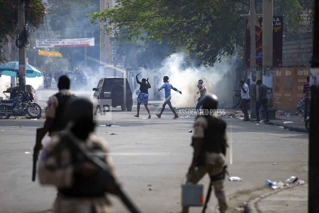 Dieu Nalio Chery People walk across the street after the police fired tear gas during a nationwide strike demanding the resignation of Haitian President Jovenel Moise in Port-au-Prince, Haiti, Tuesday, Feb. 2, 2021. (AP Photo/Dieu Nalio Chery)
