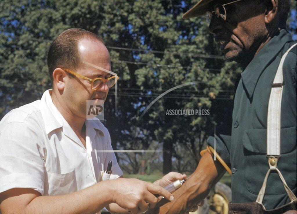 Uncredited FILE - In this 1950's file photo released by the National Archives, a black man included in a syphilis study has blood drawn by a doctor in Tuskegee, Ala. Historic failures in government response to disasters and emergencies, medical abuse, neglect and exploitation have jaded generations of black people into a distrust of public institutions. Some might call it the Tuskegee effect, referring to the U.S. government’s once-secret syphilis study of black men in Alabama that one study shows later reduced their life expectancy due to distrust of medical science. (National Archives via AP, File)