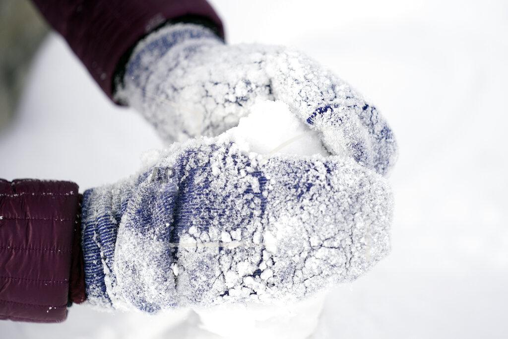 David J. Phillip Cristina Lucero's hands are covered in snow while building a snowman Monday, Feb. 15, 2021, in Houston. A winter storm dropping snow and ice sent temperatures plunging across the southern Plains, prompting a power emergency in Texas a day after conditions canceled flights and impacted traffic across large swaths of the U.S. (AP Photo/David J. Phillip)