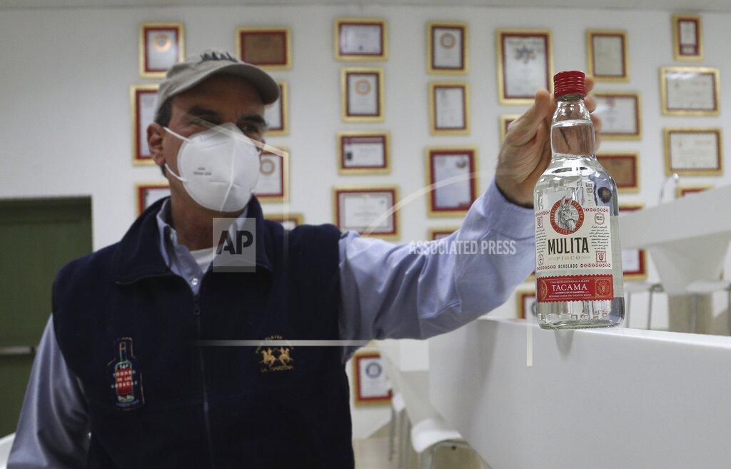 Martin Mejia Pisco producer Jose Olaechea shows a bottle of La mulita brand Pisco in his office at the Tacama vineyard in Ica, Peru, Monday, Sept. 28, 2020. More than 500 Pisco producers have seen their sales collapse by half and thousands of grape growers have had their fields ruined because of the late harvests, because of the strict lockdown implemented to stop COVID-19. (AP Photo/Martin Mejia)