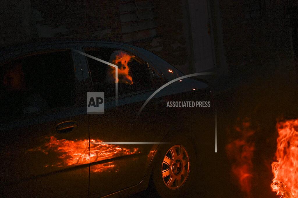 Matias Delacroix A dog inside a car watches a burning effigy representing Judas Iscariot during Holy Week in the Catia neighborhood of Caracas, Venezuela, Sunday, April 4, 2021. Most people are staying home after Holy Week activities were canceled due to the increase in infections and deaths due to COVID-19. The Burning of Judas is an Easter-time ritual in many communities, where an effigy of Judas Iscariot is hanged on Good Friday, then burned on Easter Sunday. (AP Photo/Matias Delacroix)