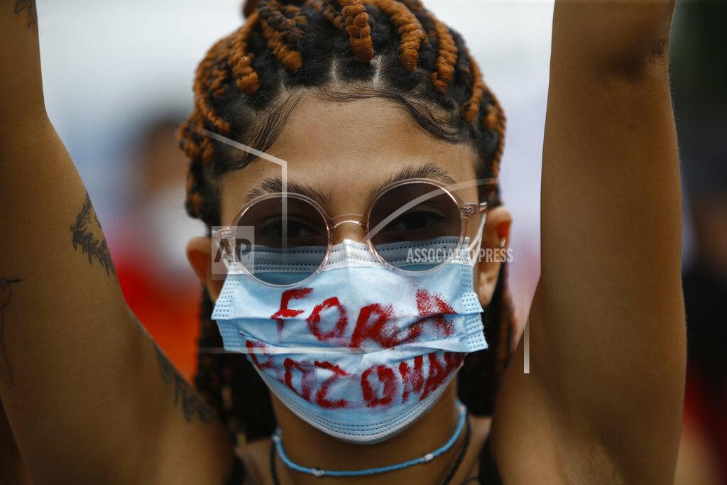 Bruna Prado A woman wearing a protective face mask marked with a message that reads in Portuguese: "Get Out Bolsonaro" during a protest against Brazilian President Jair Bolsonaro's handling of the coronavirus pandemic and economic policies they say harm the interests of the poor and working class, in Rio de Janeiro, Brazil, Saturday, June 19, 2021. Brazil is approaching an official COVID-19 death toll of 500,000 — second-highest in the world. (AP Photo/Bruna Prado)
