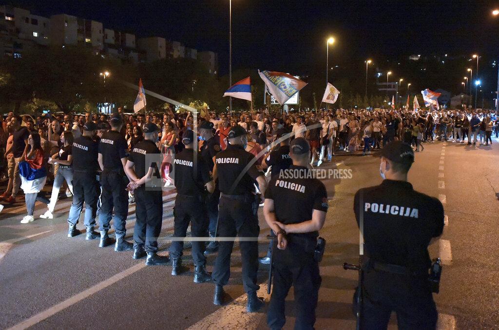 Risto Bozovic Police officers watch opposition supporters during church-led protest in Podgorica, Montenegro, Thursday, Aug. 27, 2020. Montenegro is holding a parliamentary election this weekend with the pro-Western government facing pressure over the new coronavirus outbreak and ongoing tensions in relations with Serbia and the Serbian Orthodox Church because of a religious property law. (AP Photo/Risto Bozovic)