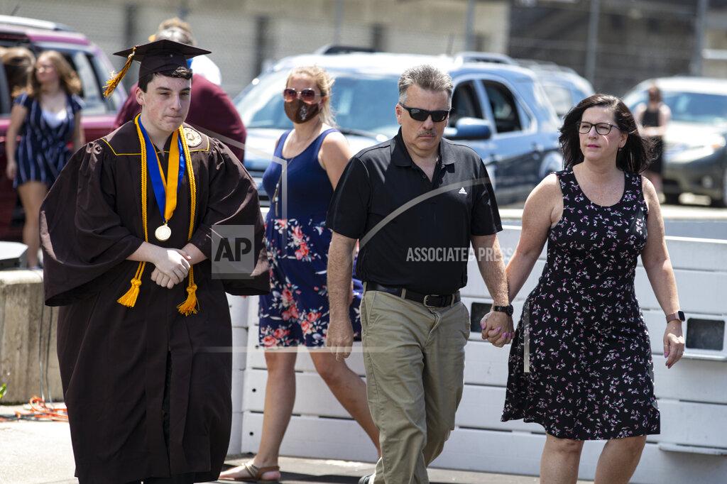Michael Conroy Jacob Foxworthy, left, walks onto the track with his parents Ted and Cindy Foxworthy to receive his Speedway High School diploma during a ceremony at the Indianapolis Motor Speedway in Indianapolis, Saturday, May 30, 2020. The ceremony was held at the track to allow for social distancing requirements due to the COVID-19 pandemic. When Ted Foxworthy was diagnosed with cancer, he set two goals: Celebrating his youngest child's 18th birthday and seeing him graduate. (AP Photo/Michael Conroy)