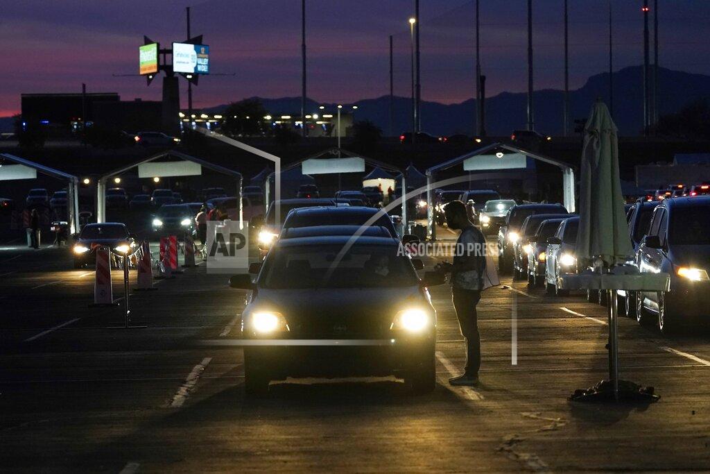 FILE - In this Jan. 12, 2021, file photo, vehicles line up so people can get their COVID-19 vaccination cards after being vaccinated in a pre-registered drive-thru in the parking lot of the State Farm Stadium in Glendale, Ariz. Arizona reported COVID-19 pandemic totals of over 800,000 confirmed cases and more than 15,000 deaths, passing the two grim milestones Wednesday, Feb. 17, 2021, after nearly 13 months since the coronavirus outbreak was first reported in the state. (AP Photo/Ross D. Franklin, File)