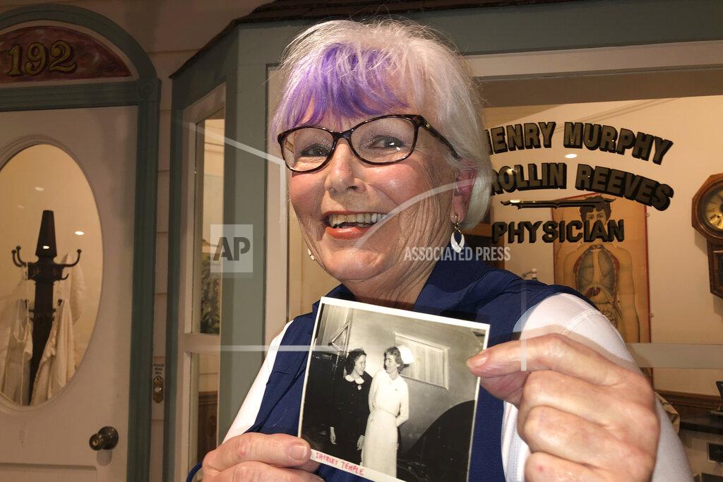 Haven Daley Nurse practitioner Sigrid Stokes, 76, holds a photograph of her mother talking to Shirley Temple, at the Salinas Valley Memorial Hospital in Salinas, Calif., Wednesday, Feb. 3, 2021. Stokes is following in her family's footsteps during the pandemic. In 1918, Stokes' mother Kristine Berg Mueller was a 14-year-old hospital volunteer in Norway during the Spanish Flu pandemic, putting her in regular contact with the deadly disease. (AP Photo/Haven Daley)