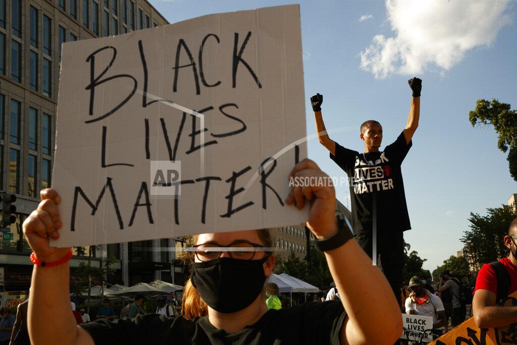 FILE - In this June 24, 2020, file photo, Antonio Mingo, right, holds his fists in the air as demonstrators protest in front of a police line on a section of 16th Street that's been renamed Black Lives Matter Plaza, in Washington. Thousands of Black activists from across the U.S. will hold the 2020 Black National Convention on Aug. 28, 2020, via livestream to produce a new political agenda that builds on the protests that followed George Floyd’s death. Organizers of the gathering shared their plans with The Associated Press on Wednesday, July 1, ahead of an official announcement. (AP Photo/Jacquelyn Martin, File)