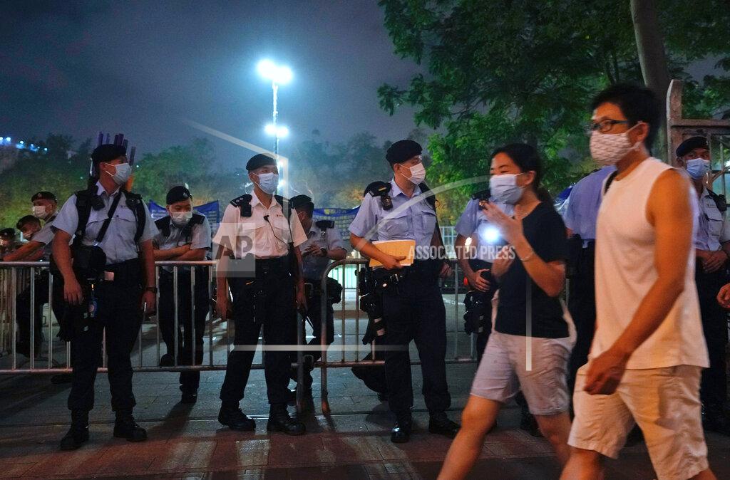 Vincent Yu People hold candles and walk past police officers near Victoria Park, a place in the past years for people to gather during a candlelight vigil to mark the anniversary of the military crackdown on a pro-democracy student movement in Beijing, in Hong Kong, Friday, June 4, 2021. A member of the committee that organizes Hong Kong's annual candlelight vigil for the victims of the Tiananmen Square crackdown was arrested early Friday on the 32nd anniversary. (AP Photo/Vincent Yu)