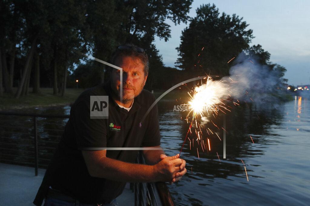 Charles Rex Arbogast Local landscaper and chairman of Saginaw Area Fireworks, Tom Roy, holds a sparkler as he poses for a portrait Monday, June 29, 2020, in Rust Park on Ojibway Island where the city's July 4th fireworks would launch over Saginaw, Mich. Roy scrambled trying to save the display, that annually drew over 150,000 people from the area, but in the end, cancelled the event amid COVID-19 issues. "People were very upset," Roy said. "They just felt they needed it, I guess." (AP Photo/Charles Rex Arbogast)