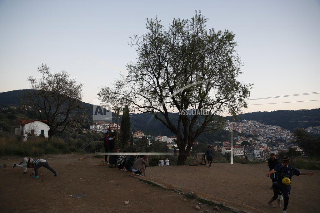 Thanassis Stavrakis Migrants play soccer outside the perimeter of the overcrowded refugee camp at the port of Vathy on the eastern Aegean island of Samos, Greece, Tuesday, Feb. 23, 2021. On a hill above a small island village, the sparkling blue of the Aegean just visible through the pine trees, lies a boy’s grave. His first ever boat ride was to be his last - the sea claimed him before his sixth birthday. His 25-year-old father, like so many before him, had hoped for a better life in Europe, far from the violence of his native Afghanistan. But his dreams were dashed on the rocks of Samos, a picturesque Greek island almost touching the Turkish coast. Still devastated from losing his only child, the father has now found himself charged with a felony count of child endangerment. (AP Photo/Thanassis Stavrakis)