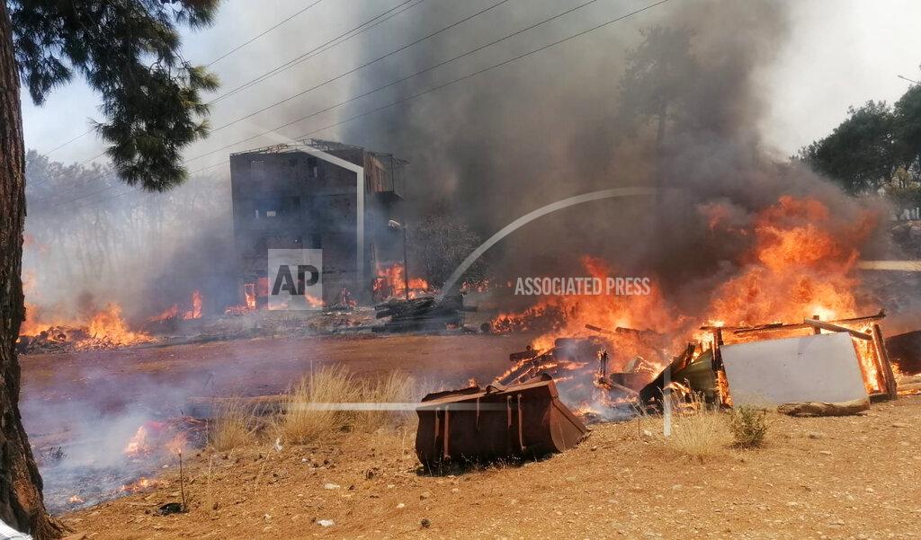 Arif Kaplan A wildfire fanned by strong winds engulfs a building near the Mediterranean coastal town of Manavgat, Antalya, Turkey, Wednesday, July 28, 2021. Authorities evacuated homes in Manavgat as a wildfire raged Wednesday through a forest. Gendarmerie forces helped move residents out of four neighborhoods in the town out of the fire's path as firefighters worked to control the blaze, the Manavgat district governor Mustafa Yigit told the state-run Anadolu Agency. (Arif Kaplan/IHA via AP)