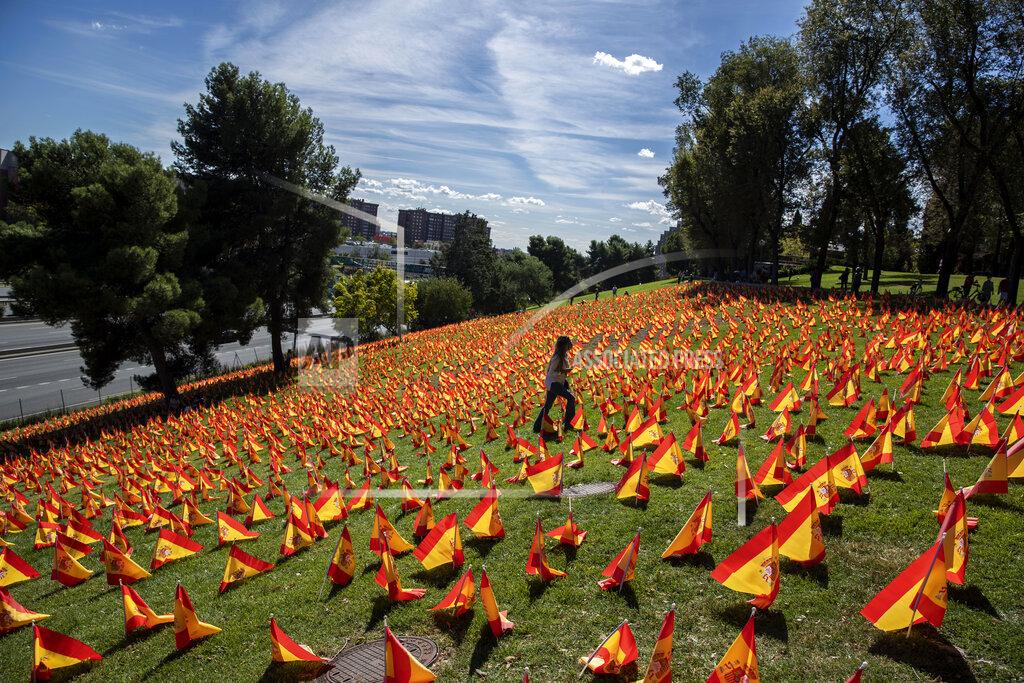 Manu Fernandez A woman walks among the Spanish flags placed in memory of coronavirus (COVID-19) victims in Madrid, Spain, Sunday, Sept. 27, 2020. An association of families of coronavirus victims has planted what it says are 53,000 small Spanish flags in a Madrid park to honor the dead of the pandemic. (AP Photo/Manu Fernandez)