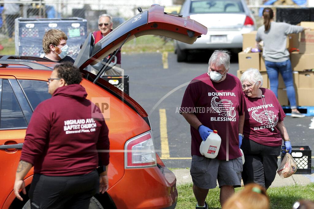 Church members Brian Helton and Donna Covert help load food during a drive-thru food distribution service Saturday, April 4, 2020, in front of Highland Avenue Baptist Church in Elmwood Place, Ohio. At least 800 vehicles passed through, each receiving a pre-packed 40-pound emergency food box with staples like peanut butter, spaghetti, canned fruits, vegetables, oatmeal, and chili, and two gallons of milk, a frozen chicken,18 eggs and produce from the Freestore Foodbank of Cincinnati, according to Jessie Fossenkemper, the community partnership manager. (Kareem Elgazzar/The Cincinnati Enquirer via AP)